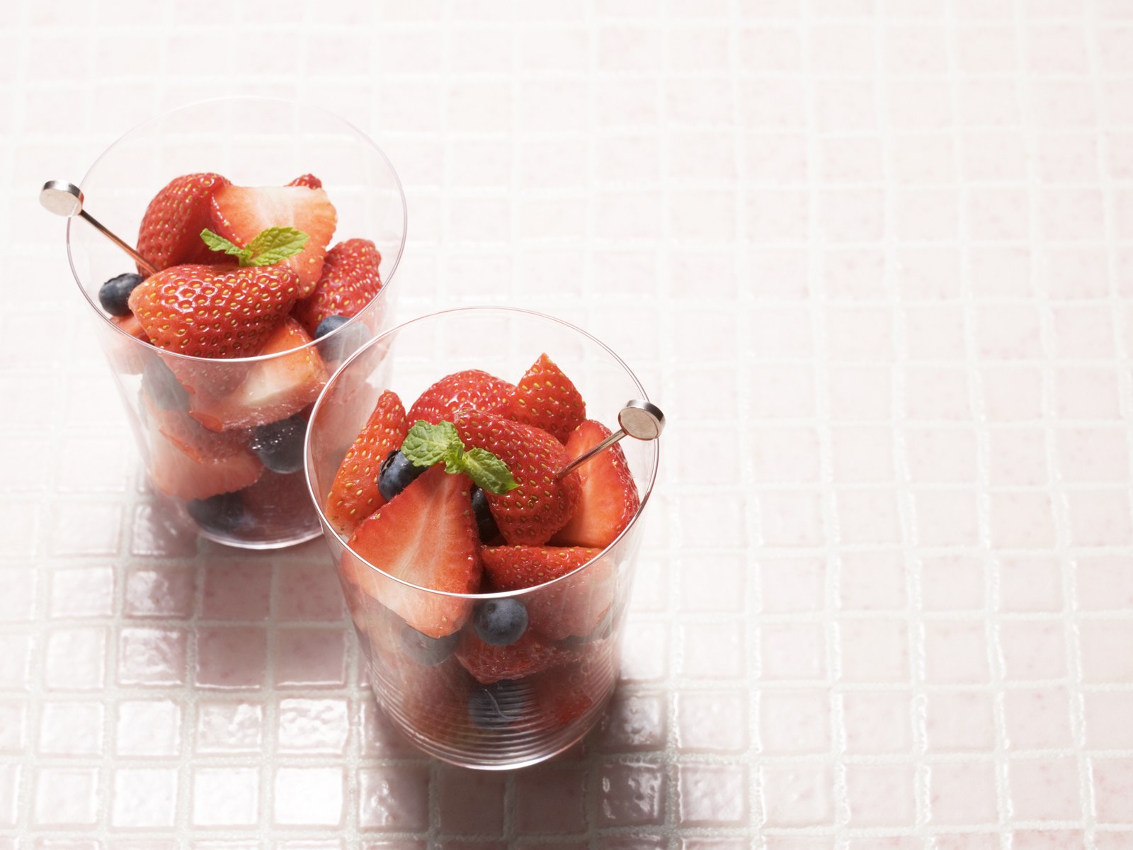 几颗草莓放进装着水的透明玻璃杯子里清新凉爽食物饮品素材设计